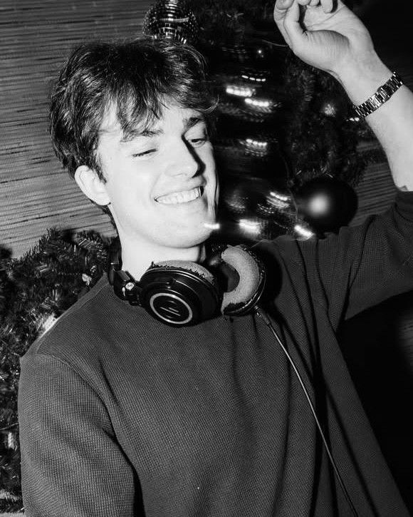 LUCOSIS at the decks, smiling, headphones around his neck.
